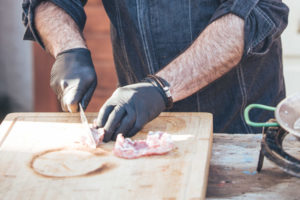 Jorge Gatell, Koch von Papa Corazón Catering bereitet in seinem Garten in Oberursel eine Paella zu. Das Fleisch wird geschnitten.