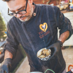 Jorge Gatell, Koch von Papa Corazón Catering, Oberursel, bei Frankfurt bereitet in seinem Garten in Oberursel eine Paella zu. Artischocken werden zum Reis hinzugefügt.