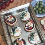 Zweierlei gefüllte Pilze mit Tomaten und Schafskäse oder mit Ziegenfrischkäse und Nüssen auf einem silbernen Tablett dekoriert mit frischem Gemüse - Fingerfood eines Caterings in Frankfurt