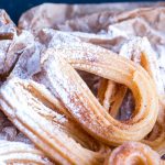 Churros mit Puderzucker auf Packpapier als Dessertidee für Party
