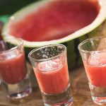 Wassermelonencocktail serviert in halber Wassermelone und kleinen Shotgläsern auf Catering Grillparty