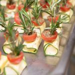 In Würfel geschnittener Schafskäse in dünne Zucchinischeibe gewickelt, oben drauf eine halbe Minitomate und als Spieß einen frischen Rosmarinzweig von Geburtstagscatering in Frankfurt am Main