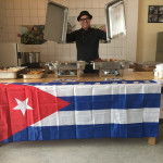 Jorge Gatell, Koch von Papa Corazón Catering präsentiert seine kubanischen Spezialitäten in der Casa Cultural Cubana in Frankfurt im Mehrgenerationenhaus auf einem Tisch mit Kuba-Flagge