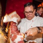 Partyservice Koch Papa Corazon schneidet Schinken vom Bein auf Feier