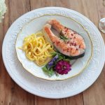 Festlicher mediterraner Lachs mit Nudeln auf festlichem weißen Geschirr mit weißen Blumen für Hochzeitsbüffet