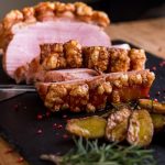 Deutscher Braten mit spanischen Rosmarinkartoffeln auf schwarzer Schieferplatte angeschnitten für deutsches Büffet