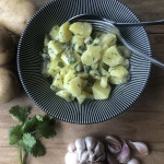 Schwarze Schale mit Kartoffel-Apfel-Salat und frischen Gartenkräutern