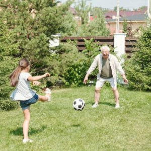 Fußball spielendes Mädchen mit Opa
